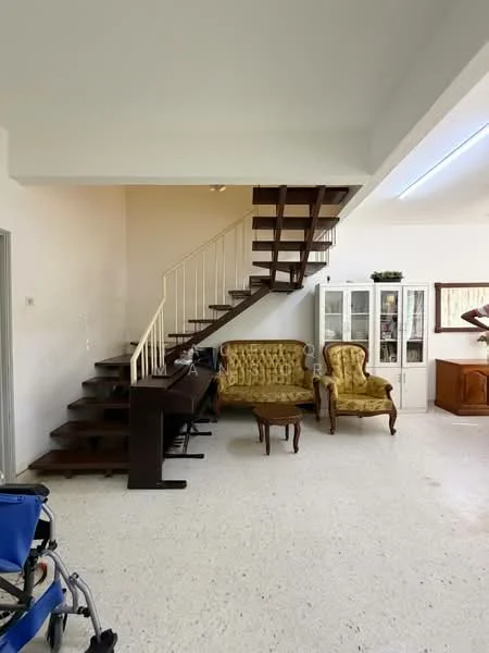Living features: wooden staircase, cream painted walls, white ceiling, tile flooring, two upholstered armchairs in yellow, wooden coffee table, wooden console table, glass display cabinet, natural light from windows, open layout; style: traditional.