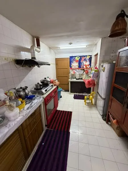 Kitchen features: red gas stove, stainless-steel range hood, white tiled walls, white tiled flooring, wood cabinetry, double-basin sink, refrigerator, kitchen countertop, hanging light fixture, purple striped area rug, various cooking pots, kitchen utensils, window with curtain, wooden door, plastic storage containers.