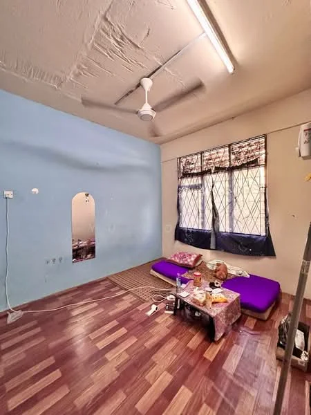 Bedroom features: purple mattress on the floor, wooden flooring, blue painted walls, two windows with black grills, sheer curtains, ceiling fan, mirror on the wall, area rug, decorative items on the floor.