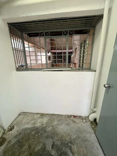 Room features: concrete flooring, white painted walls, metal security grille window, door with handle, visible plumbing pipes.