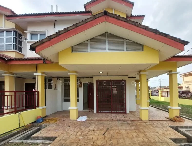 Exterior type: linked terrace house; features: yellow painted facade, red tiled roof, covered porch area, front entrance with security grille, paved walkway, manicured lawn, two-storey structure, balcony on upper level, visible windows with grills, surrounded by grass, exterior lighting fixtures; style: modern.