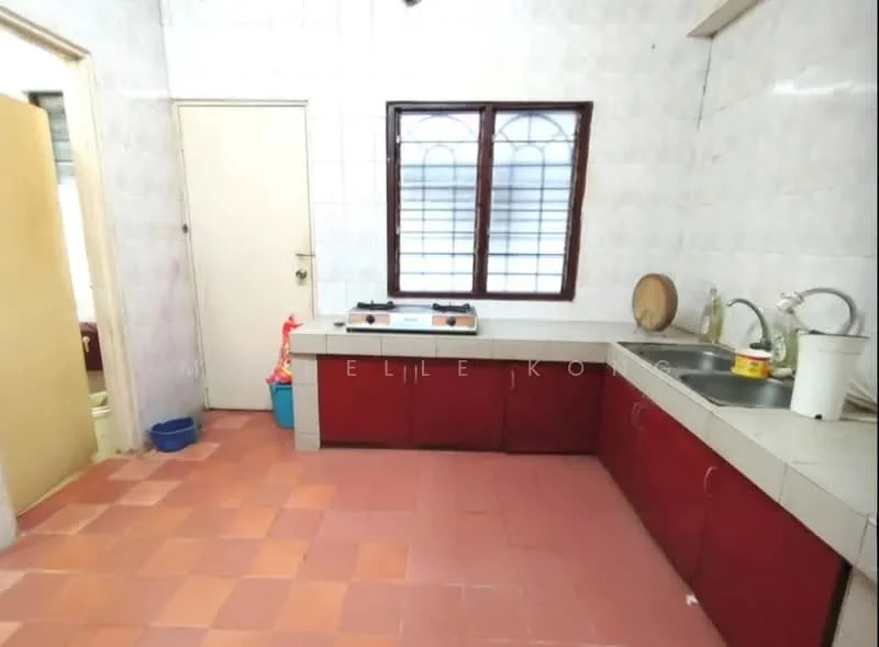 Kitchen features: white tiled walls, red cabinetry, grey countertop, double-bowl stainless-steel sink, chrome pull-down faucet, gas stove with two burners, window with grid pattern, terracotta tile flooring, door leading to another room.