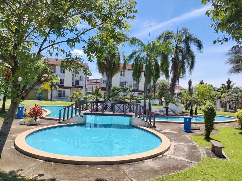 Exterior type: landscape garden; features: swimming pool with circular shape, bridge over the pool, manicured lawn, palm trees, tropical landscaping, surrounding residential buildings, garden pathways, decorative shrubs; style: tropical-modern.