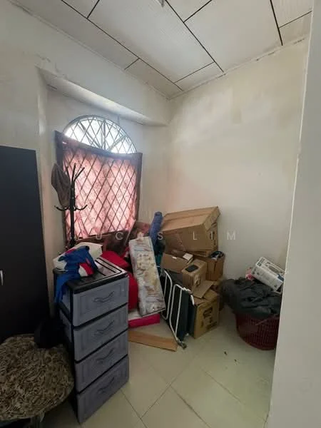 Room features: window with decorative grille, light-colored walls, tile flooring, cluttered with boxes and items, plastic storage drawers, small chair, basket, various household items.