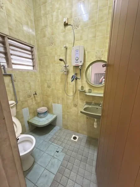 Bathroom features: green tiled walls, blue tiled flooring, one-piece toilet, sink with green countertop, round mirror, shower with wall-mounted faucet, water heater, window with horizontal slats.