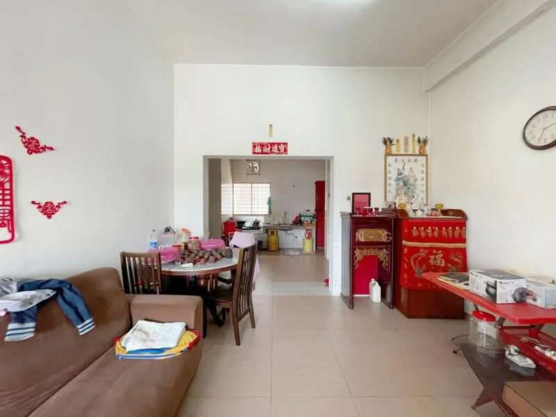 Living features: beige wall, tile flooring, brown fabric sofa, wooden dining table with chairs, decorative wall art, wall clock, red cabinet, open layout to kitchen, window with natural light. Kitchen features: white cabinetry, kitchen counter, sink, stove, refrigerator, window, tile flooring.