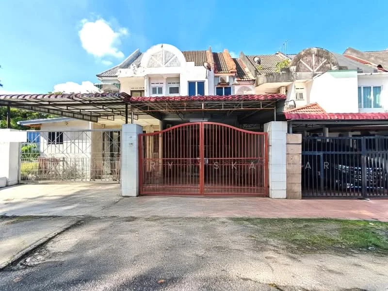 Exterior type: linked terrace house; features: red metal gate, paved driveway, car porch with awning, two-storey structure, tiled roof, white painted facade, mature landscaping, visible parking area, surrounded by greenery, front yard, balconies on upper level; style: modern.