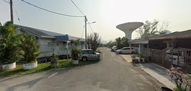 Exterior features: paved road, water tower in background, single-storey houses, landscaped garden with palm trees, driveways visible, street lighting, utility poles, residential neighborhood.