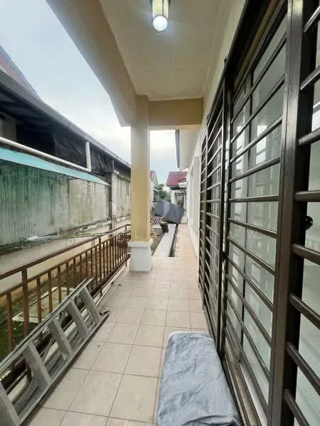 Room features: tiled flooring, metal railing, sliding glass doors, overhead lighting, exterior wall with paint, narrow walkway, adjacent to a building, visible drainage area.