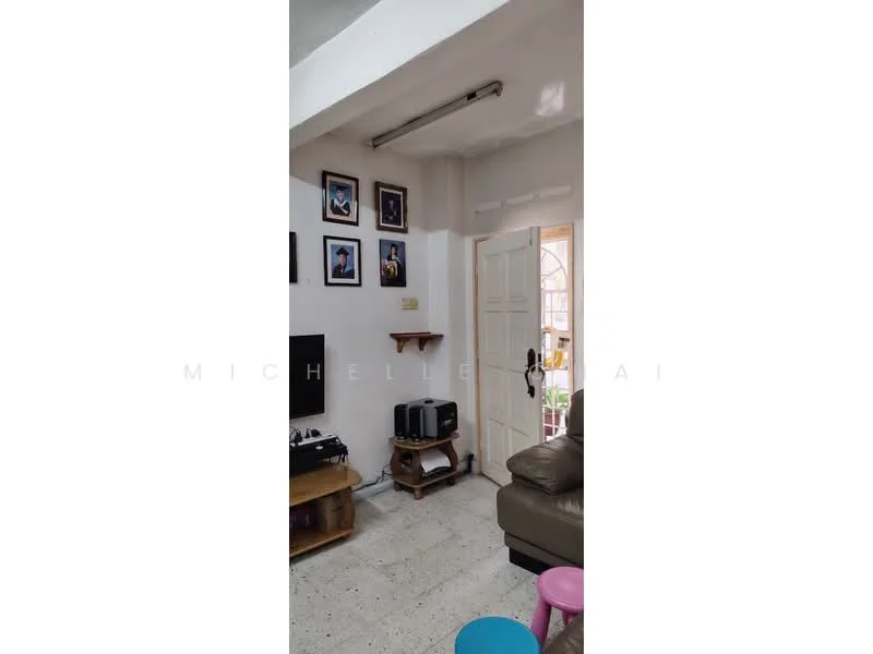 Living features: white painted walls, light grey ceiling, tile flooring, wall-mounted TV, wooden TV console, framed artwork on walls, door leading to outdoor area, shelf mounted on wall, leather sofa, colorful stools; style: modern.