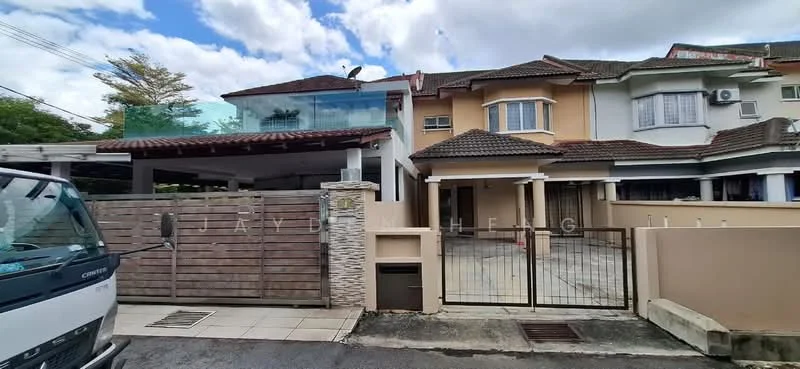 Exterior type: linked terrace house; features: two-storey building, cream painted facade, brown tiled roof, glass balcony railing, stone cladding at entrance, wooden gate, paved driveway, front garden area, air conditioning unit visible, fenced perimeter; style: modern.