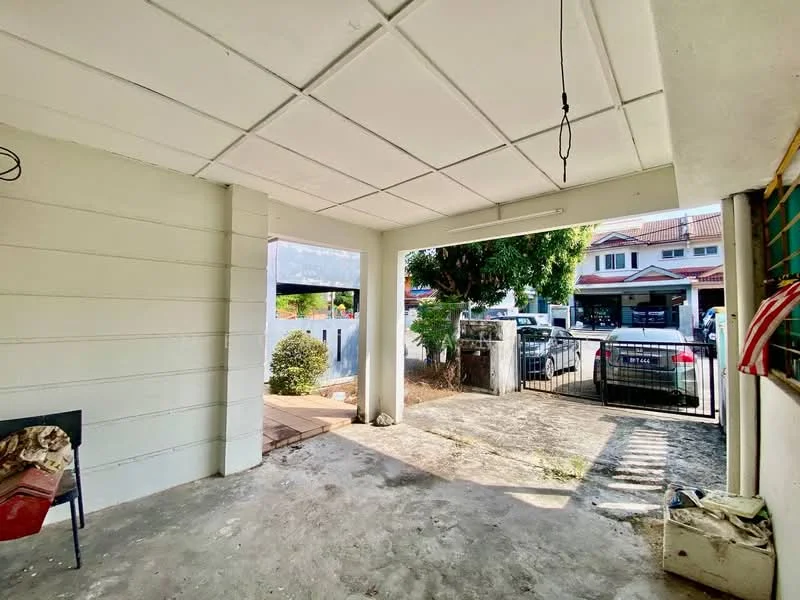 Exterior type: car porch; features: concrete flooring, white painted walls, flat ceiling, single entrance gate, manicured shrubbery, visible parked cars, fenced perimeter, outdoor lighting; style: modern.