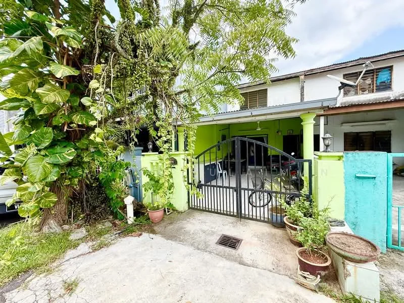 Exterior type: semi-detached house; features: green painted facade, metal gate, driveway with concrete surface, potted plants, mature trees, exposed brick wall, car porch, single-storey, surrounded by greenery; style: traditional.