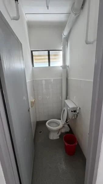 Bathroom features: white tiled walls, grey flooring, toilet, sink, window, pipe fittings, red bucket.
