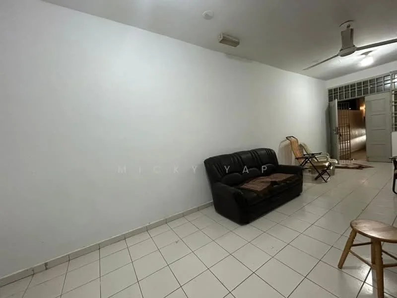 Living features: white painted walls, tile flooring, 3-seater black leather sofa, ceiling fan, wooden folding chair, wooden stool, open space, natural light from doorway.