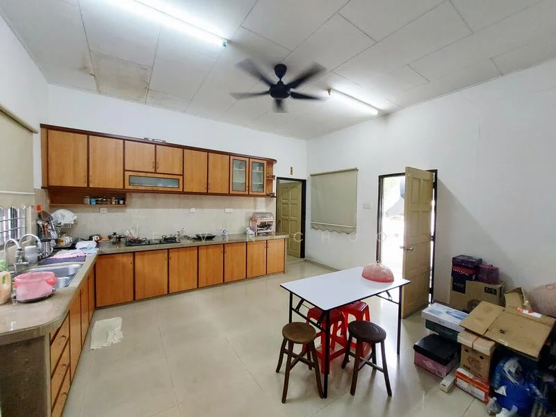 Kitchen features: brown wooden cabinetry, granite countertop, stainless-steel sink, built-in oven, freestanding gas range oven, exhaust hood, ceramic tile flooring, ceiling fan, window with blinds, dining table with white surface, two red plastic chairs, open shelving, refrigerator, various kitchen appliances, storage boxes.