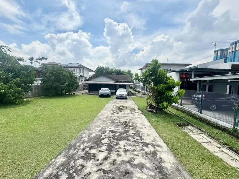 Exterior type: detached bungalow; features: manicured lawn, concrete driveway, two parked cars, surrounding greenery, single-storey building, clear blue sky, clouds, adjacent houses, fenced perimeter, paved walkway; style: traditional.