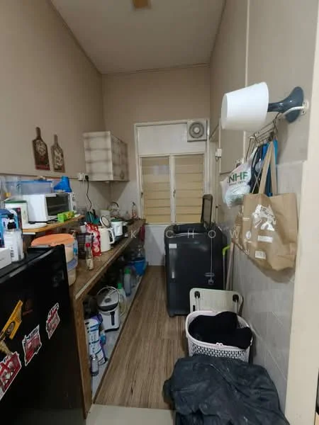 Laundry features: wooden flooring, white painted walls, built-in shelving, black fridge, microwave, washing machine, plastic laundry basket, various cleaning supplies, clothes drying rack, door leading to another room, wall-mounted light fixture, stacked storage boxes.