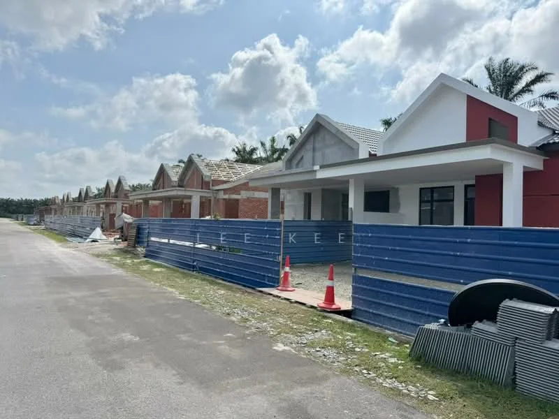Exterior type: linked terrace house; features: newly constructed houses, red and white facade, grey roof tiles, blue construction fencing, paved road, landscaped area with grass, surrounding palm trees, unfinished exterior, construction materials visible; style: modern.