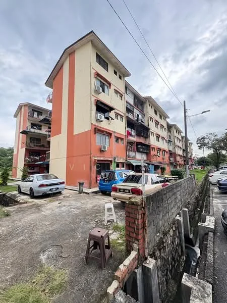 Exterior type: low-rise apartment block; features: red and cream painted facade, 3-storey building, balconies with railings, visible air conditioning units, parking area with multiple cars, surrounding greenery, sidewalk, street lighting; style: contemporary.