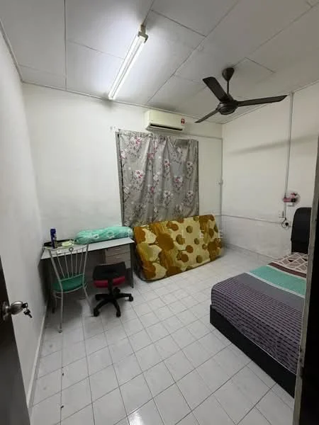 Bedroom features: white painted walls, ceiling fan, wall-mounted air conditioning unit, single bed with dark headboard, green bedding, sofa with floral pattern, desk with chair, tile flooring, curtains with floral pattern, light fixture on ceiling.