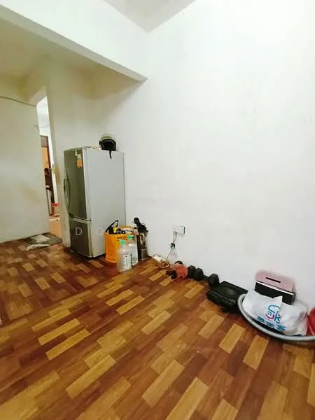 Room features: wooden flooring, white painted walls, refrigerator, plastic storage container, exercise weights, black shoes, wall socket.