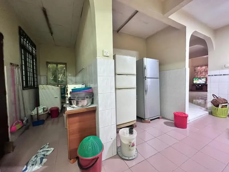 Kitchen features: white tiled walls, pink tiled flooring, double-door fridge, single-bowl stainless-steel sink, wooden countertop, kitchen cabinets, washing machine, plastic storage bins, green plastic basket, red plastic bin.