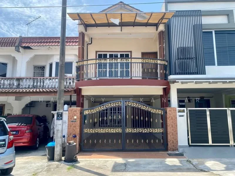 Exterior type: linked terrace house; features: two-storey building, black wrought iron gate with gold accents, balcony with decorative railing, red brick facade, white painted walls, roof overhang, manicured front yard, driveway with parking space, adjacent to another linked terrace house; style: modern.