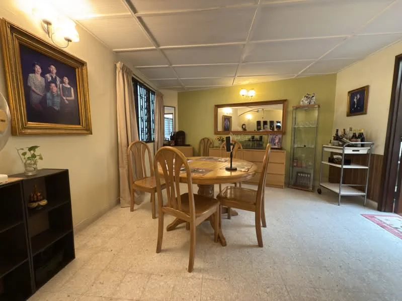 Dining features: round wooden dining table, 4 wooden dining chairs, cream painted walls, white ceiling with grid pattern, wall-mounted light fixture, framed artwork on wall, curtains on window, wooden sideboard, glass display cabinet, decorative items on shelves, carpet on floor; style: traditional.