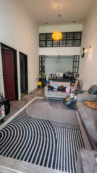 Living features: grey fabric L-shape sectional sofa, black and white area rug with abstract pattern, white painted walls, exposed concrete flooring, pendant light fixture, wall-mounted TV, coffee table, decorative wall clock, open shelving unit, large windows with black frames, decorative plants, art easel, stack of folded clothes; style: modern.
