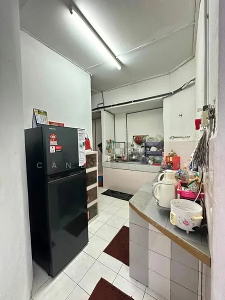 Kitchen features: black fridge, white tiled flooring, white painted walls, countertop with storage underneath, sink, kettle, toaster, various kitchen utensils, open shelving, multiple cabinets, fluorescent ceiling lights.