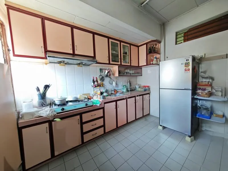 Kitchen features: pink and cream cabinetry, stainless-steel sink, chrome faucet, built-in stove, exhaust hood, white tiled backsplash, countertop with clutter, refrigerator, open shelving, floor tiles, window with grill, various kitchen appliances, bottles and condiments on countertop.