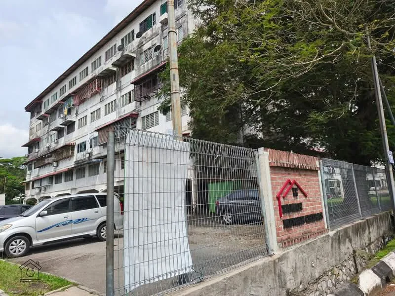 Exterior type: low-rise apartment block; features: white painted facade, balconies with metal railings, multiple windows, brick wall at the front, fenced perimeter, surrounding greenery, parking area visible, two-storey building, street view; style: traditional.