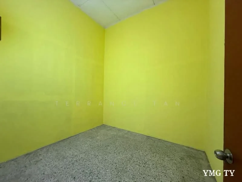 Room features: yellow painted walls, concrete flooring, single door, no visible windows, plain ceiling.