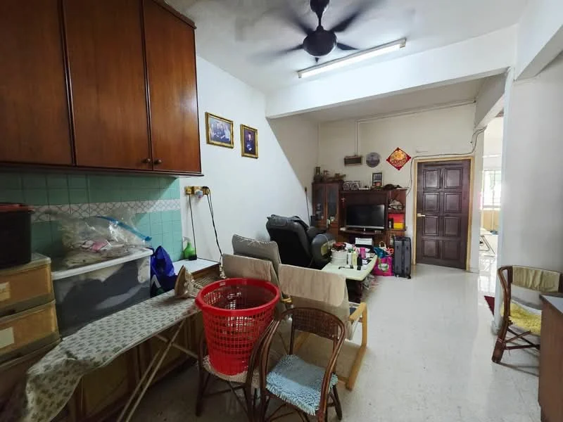 Living features: ceiling fan, wall-mounted TV, wooden cabinetry, green tiled backsplash, white walls, light-colored flooring, dining table with chairs, plastic storage bins, red laundry basket, armchair, sofa, decorative wall art.
