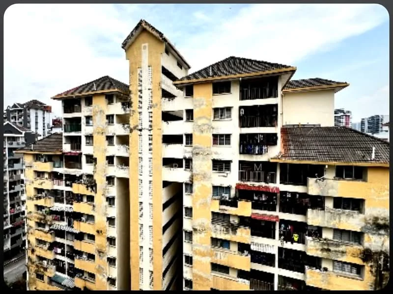 Exterior type: low-rise apartment block; features: yellow painted facade, exposed concrete, pitched tile roof, balconies with railings, multiple storeys, visible wear and tear on exterior, surrounded by urban environment; style: traditional.