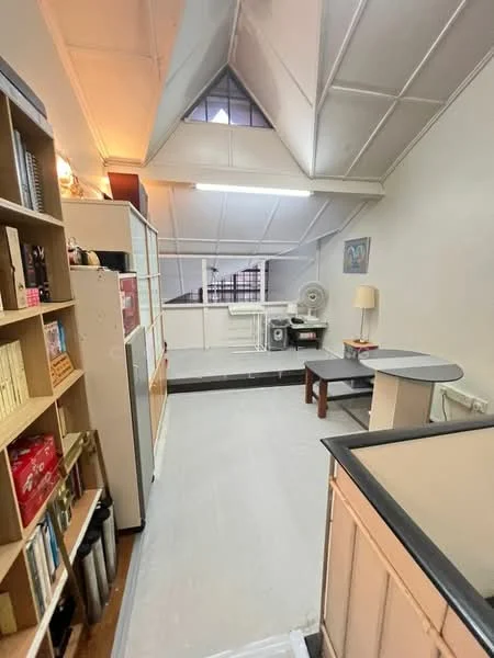 Room features: sloped ceiling, white painted walls, light wood flooring, built-in shelving unit, small round table, desk with chair, window with grid pattern, ceiling fan, light fixture, open space layout; style: modern.