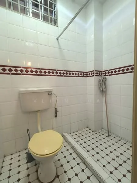 Bathroom features: white tiled walls, red decorative border tiles, white mosaic floor tiles, one-piece toilet, shower area with glass partition, shower head, towel rack, cleaning mop, drainage channel.