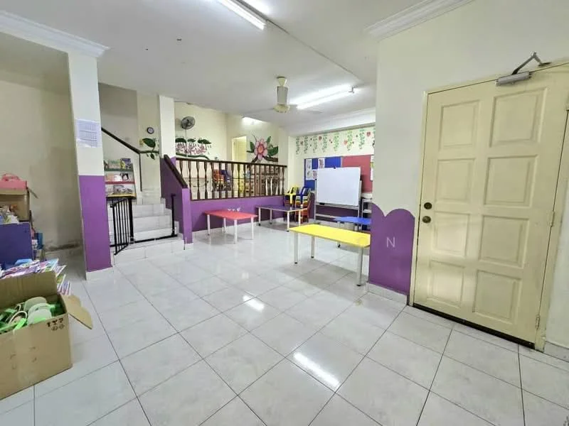 Room features: white tiled flooring, cream painted walls, purple accent wall, wooden staircase, ceiling fan, wall-mounted air conditioning unit, bookshelves, tables with yellow and red surfaces, whiteboard, decorative wall with floral pattern, door with panel design; style: modern.