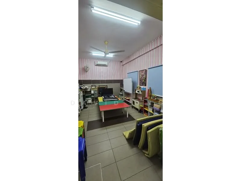 Room features: ceiling fan, fluorescent lighting, light grey tiled flooring, pink striped wallpaper, white walls, built-in shelves, green upholstered chairs, table with red tabletop, air conditioning unit, whiteboard, decorative artwork.