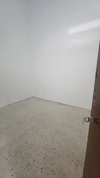 Room features: white painted walls, concrete flooring, single door, natural light from window.