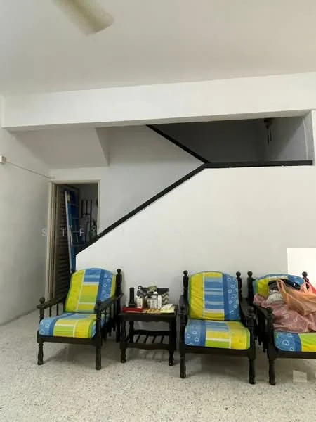 Living features: three wooden armchairs with blue and green cushions, coffee table, textured flooring, white painted walls, staircase leading to upper floor, ceiling fan, decorative items on coffee table, open space layout.