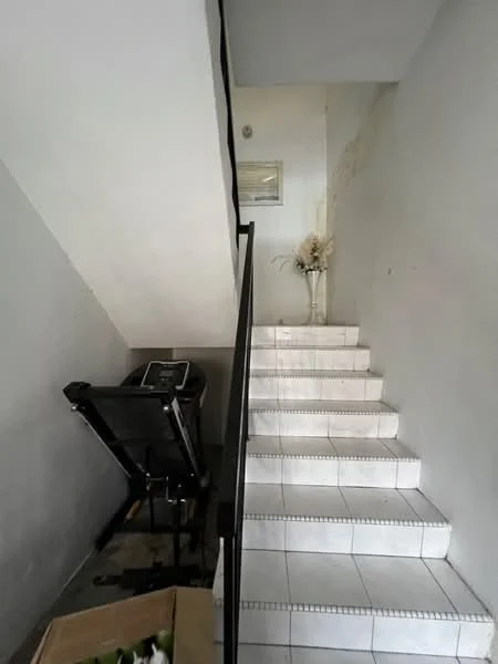 Room features: white painted walls, white tiled flooring, staircase with white tiles, black metal railing, decorative vase with flowers, wall-mounted light fixture, staircase landing, exercise equipment; style: minimalist.