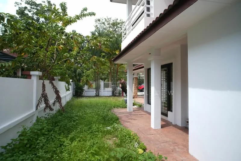 Exterior type: detached bungalow; features: white painted facade, flat roof, single-storey, manicured lawn, tropical landscaping, stone-paved walkway, surrounded by mature greenery, covered porch, fenced yard; style: modern.