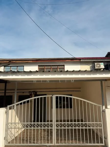 Exterior type: linked terrace house; features: metal gate, white painted facade, flat roof, air conditioning unit visible, paved walkway, overhang roof, windows with wooden frames; style: traditional.