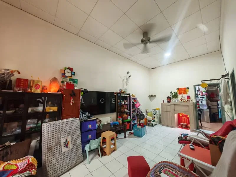 Room features: white painted walls, square ceiling tiles, ceiling fan, white tiled flooring, various decorative items, shelves with storage boxes, small table, red sofa, television unit, kitchen area visible in background.