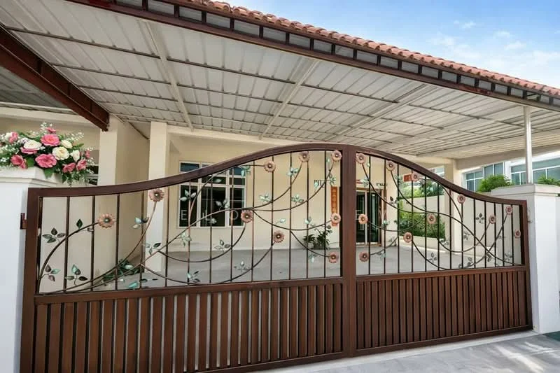 Exterior type: detached bungalow; features: decorative wrought iron gate with floral design, covered car porch, red tiled roof, white painted facade, manicured landscaping, paved driveway, large windows, front porch area; style: modern.