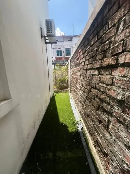 Exterior features: narrow side yard, brick wall, artificial grass, air conditioning unit mounted on wall, sunlight exposure, surrounding residential buildings.