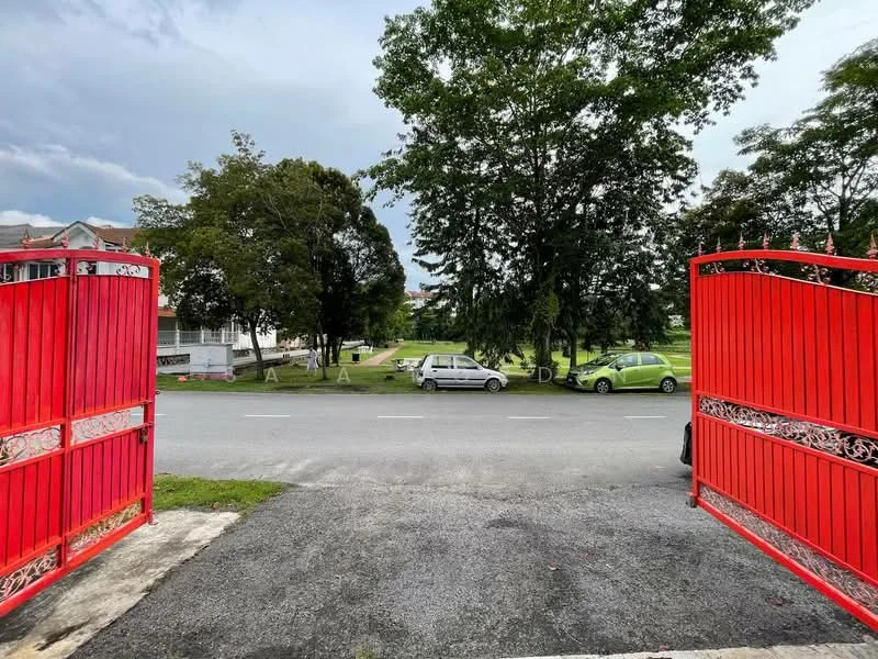 Exterior features: red wrought iron gates, gravel driveway, manicured lawn, mature trees, street view, parked cars, greenery in background.