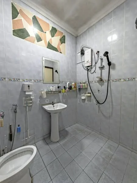 Bathroom features: white ceramic toilet, pedestal sink, mirror with decorative border, shower with handheld showerhead, wall-mounted water heater, grey ceramic wall tiles, light grey ceramic floor tiles, decorative wall panel with geometric pattern, toilet paper holder, soap dispenser, towel rack; style: modern.